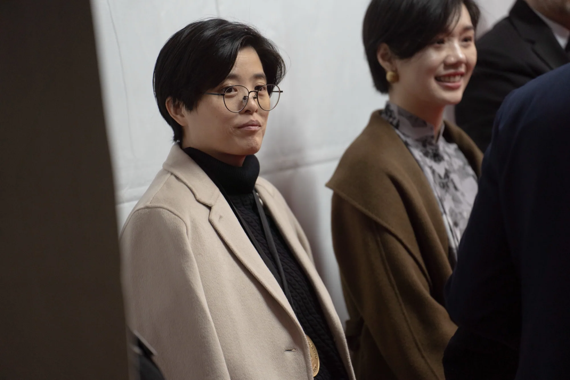 楊双子が 2024 年 11 月 20 日、ニューヨークの全米図書賞授賞式で、濃色の上着を着てトロフィーの横に静かな表情で立っている