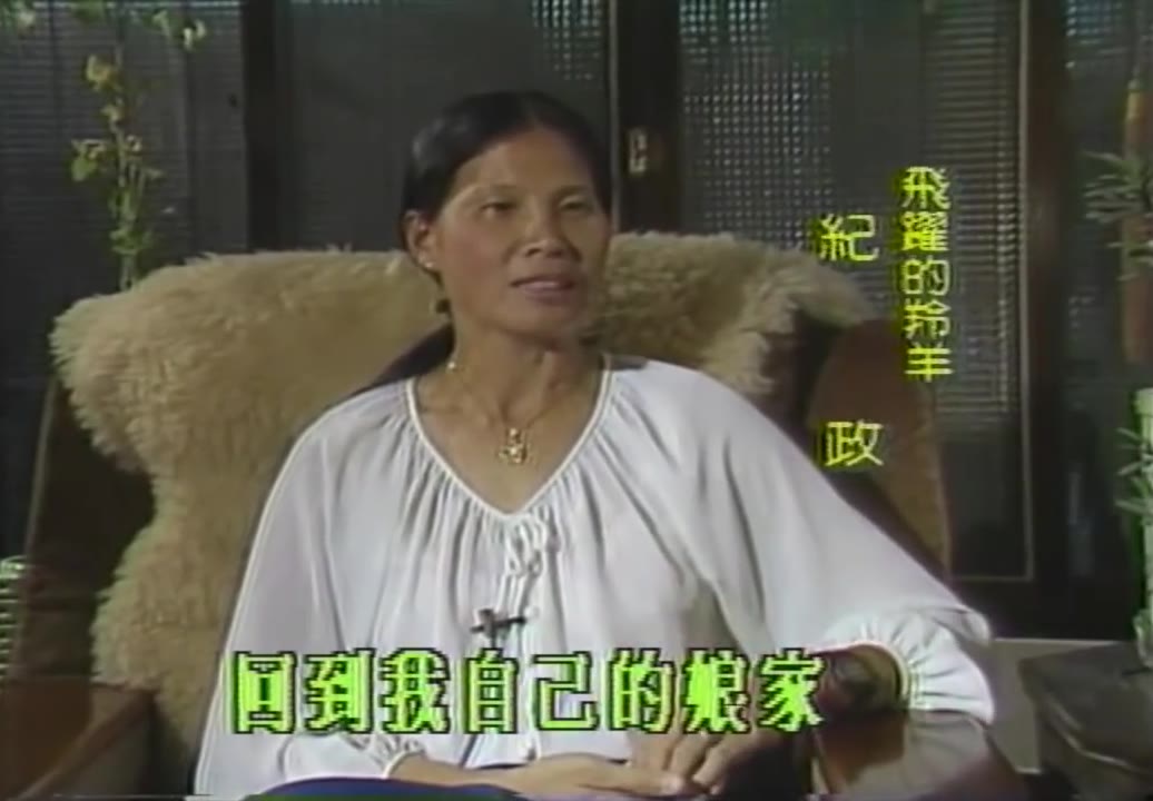 Chi Cheng sentada en una silla con reposabrazos de piel durante una entrevista, vistiendo una blusa blanca de mangas anchas, con una tarjeta de texto en verde y amarillo alineada verticalmente en el lado derecho de la pantalla que dice «La gacela voladora Chi Cheng»