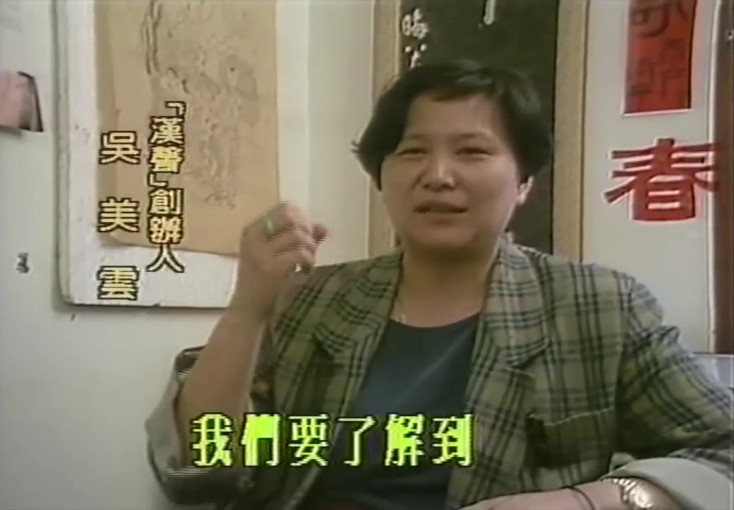 Wu Mei-yun sentada frente a una pared con caligrafía y un couplet de primavera con el carácter «primavera», vistiendo una chaqueta de cuadros, levantando la mano mientras habla. A la izquierda, una tarjeta de texto en escritura vertical dice «Fundadora de 《Hansheng》 Wu Mei-yun», y en el subtítulo inferior dice «Tenemos que entender»