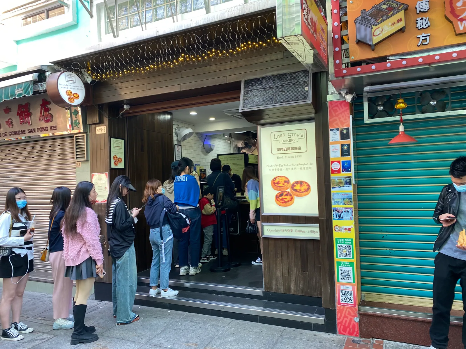 마카오 거리의 붉은 벽돌 건물, 입구에 Lord Stow's Bakery 간판이 걸려 있고 가게 앞으로 행인이 오간다