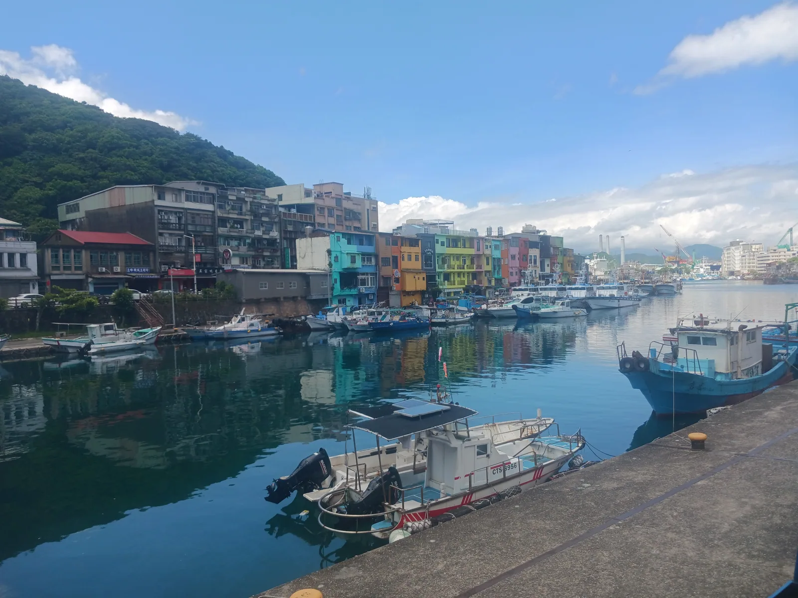 正濱漁港彩色街屋，港邊一整排老房子刷成不同顏色，前方漁船並排停靠。林右昌任市長期間，跟文大景觀系郭瓊瑩主任合作把這排房子刷成 55 種色彩。