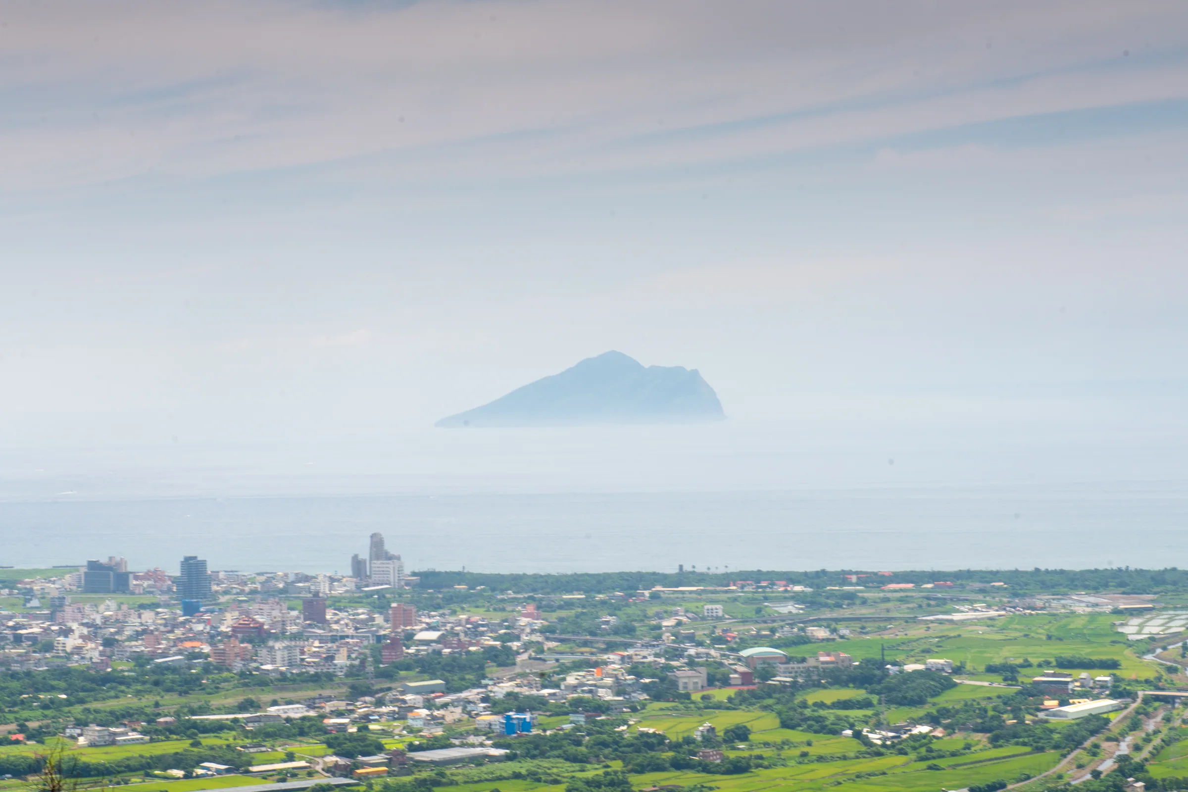 The Lanyang Plain and Guishan Island, 2019. Surrounded by mountains on three sides and opening eastward toward the Pacific, the plain is shaped like a dustpan. Annual rainfall is 2,500–3,000 millimeters on the plain and up to 5,500 millimeters in the mountains.
