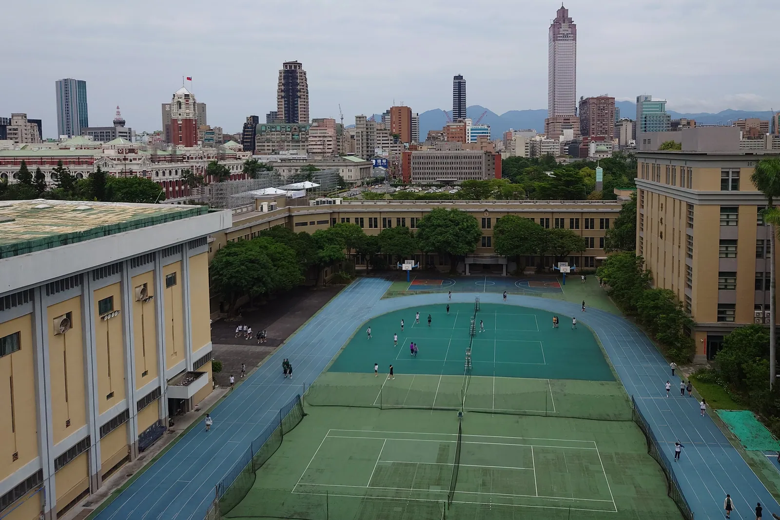 從高處俯看北一女校園，操場與球場外圍是校舍，再往外就是博愛特區的街廓；左後方紅磚建築即總統府
