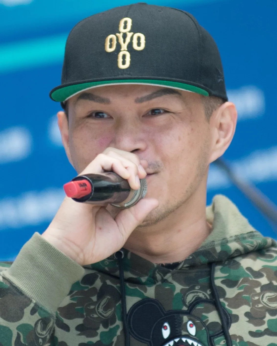 Rapper Dwagie performing on the New Year's Eve Festival stage, holding a microphone, intensely engaged, with stage lights in the background.