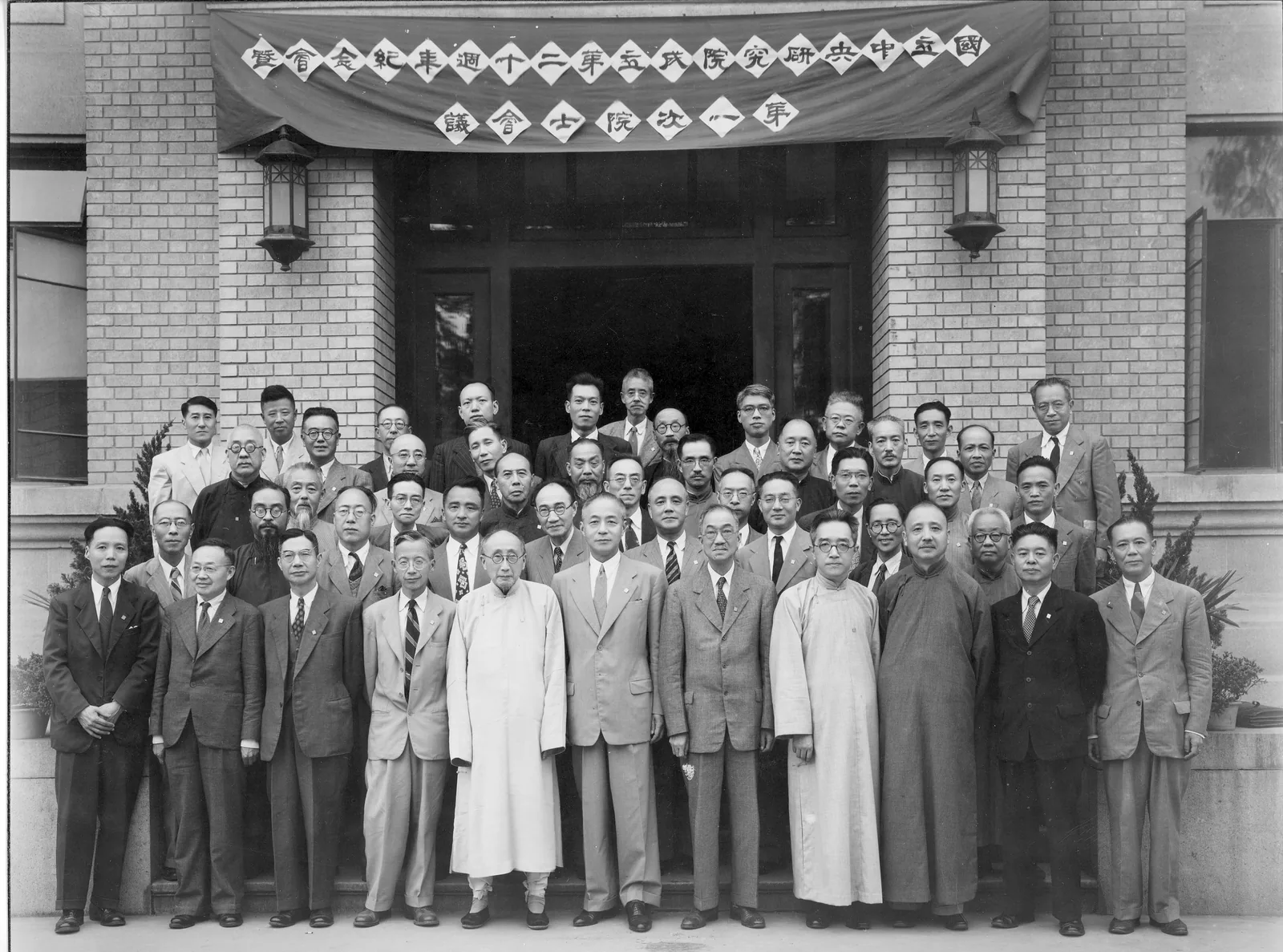 1948 年中央研究院第一屆院士合影，數十位學者身穿長袍與西裝在建築物前排成數列