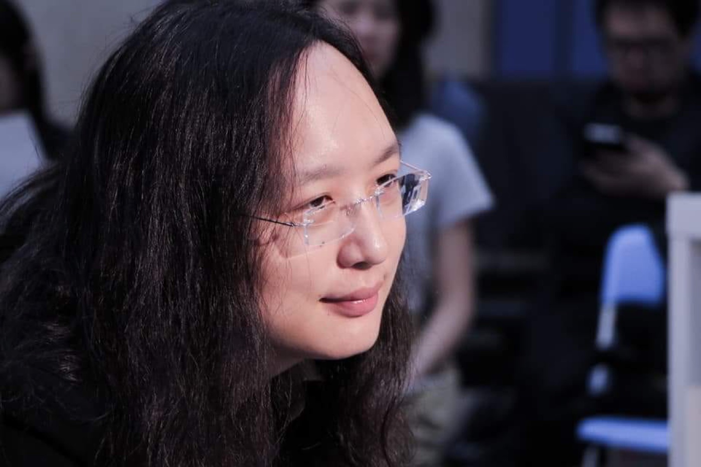 唐鳳的側臉特寫,在對談現場專注聆聽,背景是柔和的暖色燈光