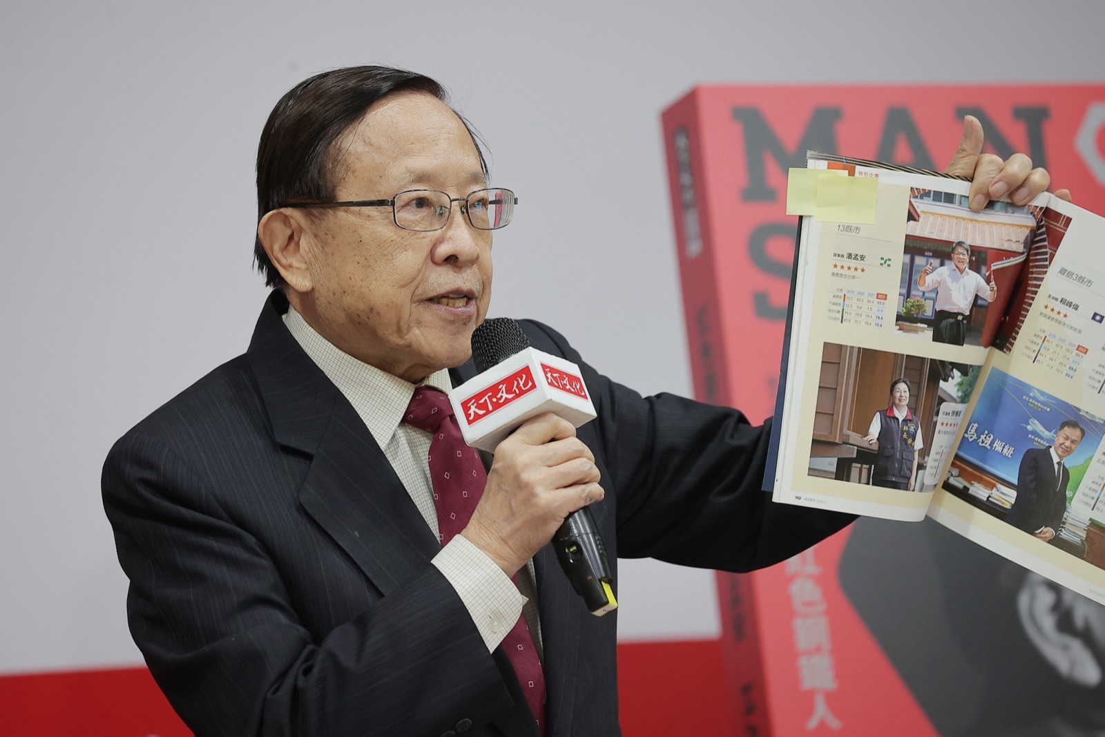 Kao Hsi-chun speaking at a podium, wearing a dark suit, at what appears to be a book launch event