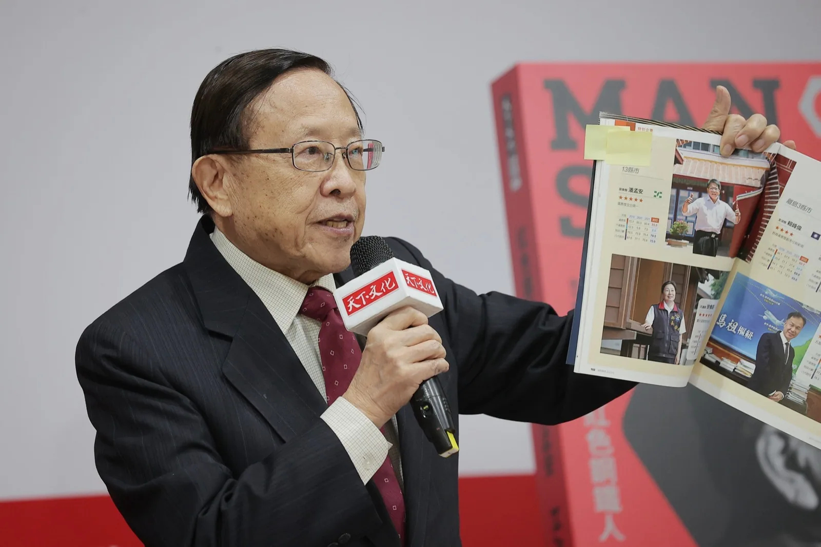 高希均站在講台前致詞，身著深色西裝，背景為書籍發表會場