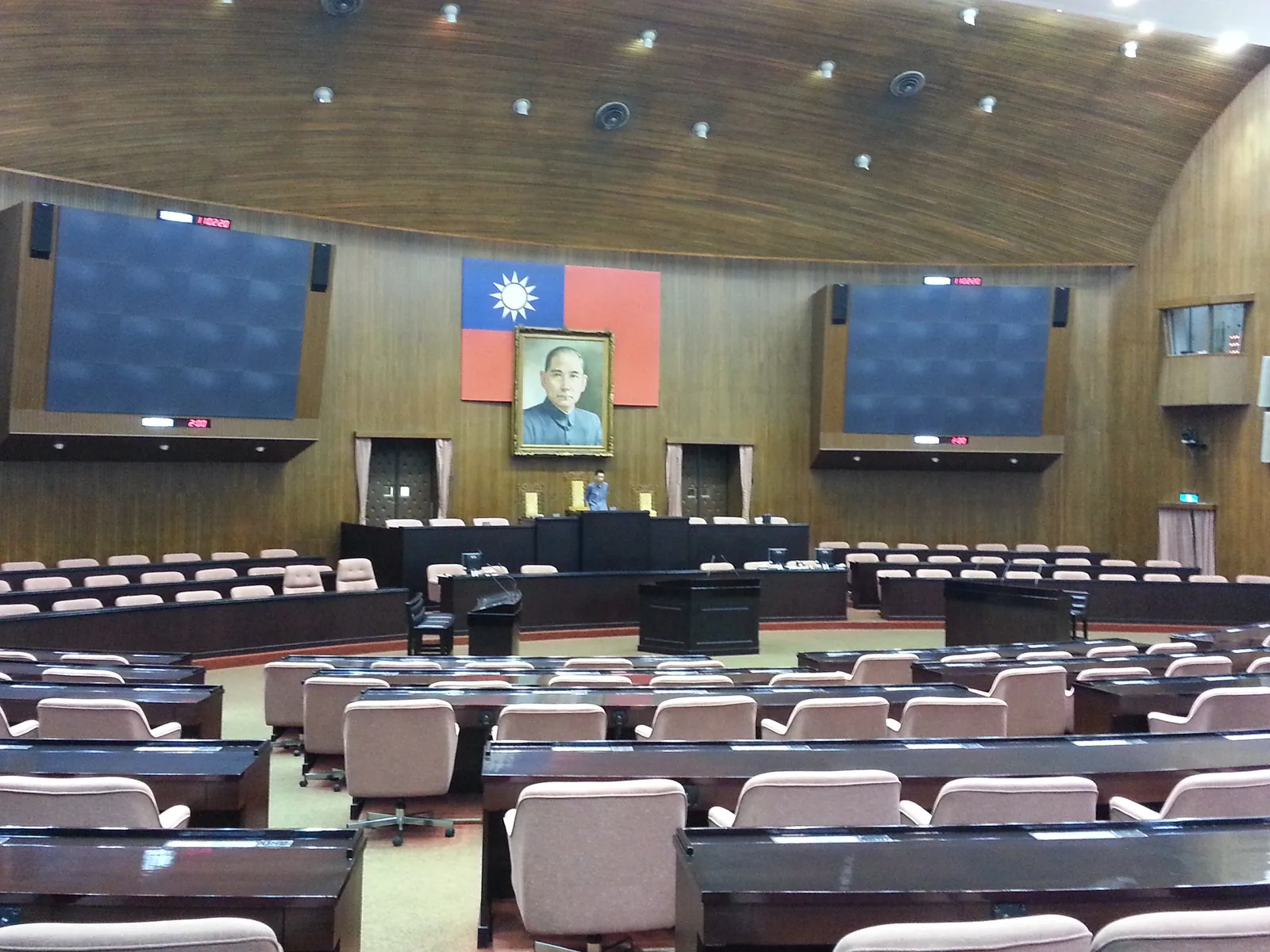 Interior da câmara do Legislativo da República da China, fileiras de assentos azuis voltados para a tribuna, onde a emenda à proporção de enfermeiros por turno foi aprovada em terceira leitura