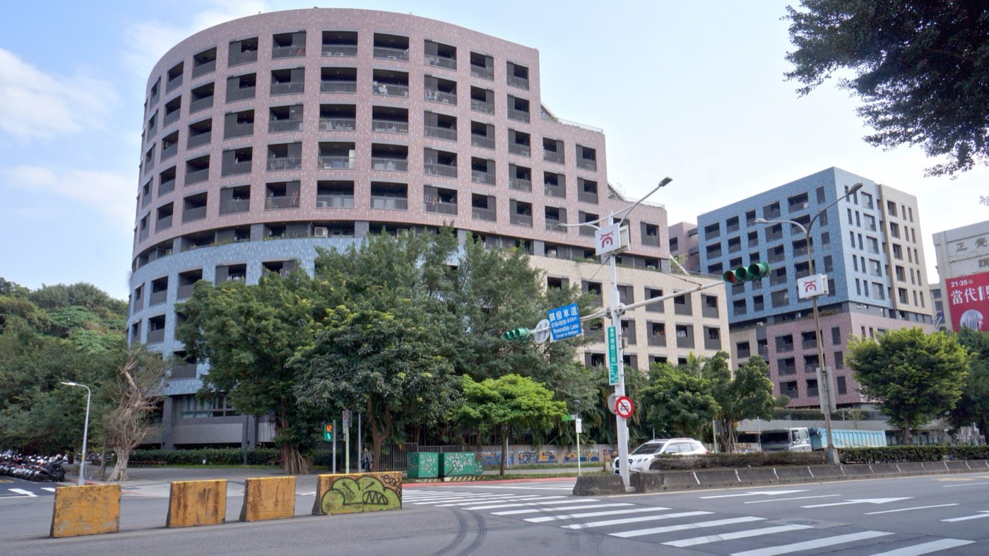 台北市大同區明倫社會住宅正面，多層現代公共住宅建築，立面整齊的米白色塔樓