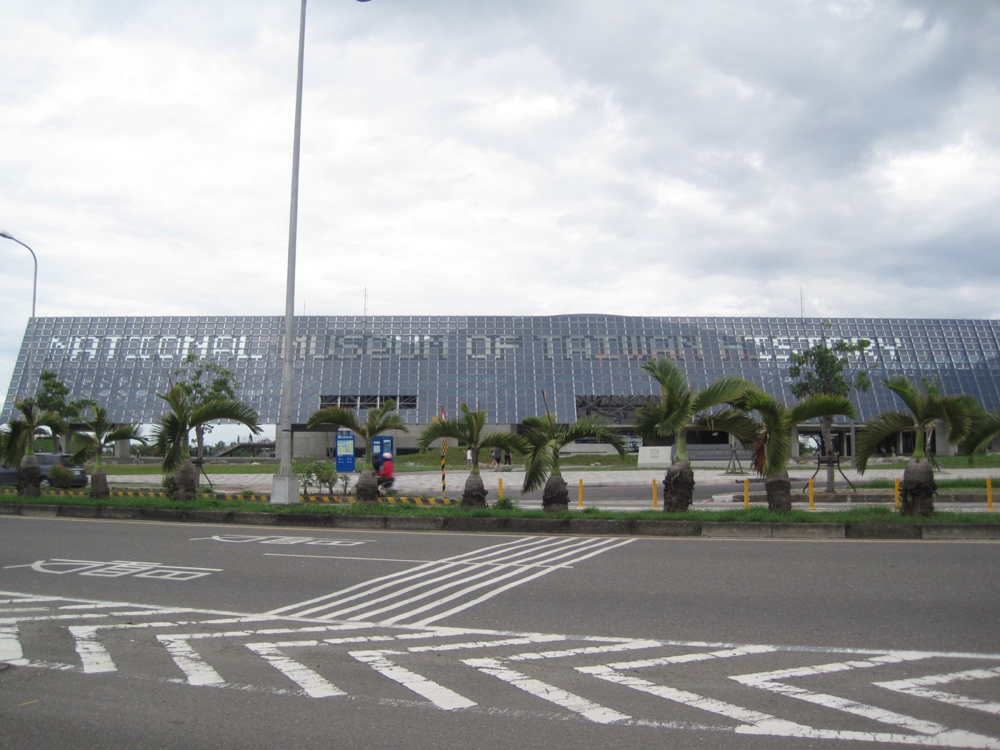 國立臺灣歷史博物館展示教育大樓側面，雲牆光電板與水池構成的建築語彙，遠處可見渡海步道穿越水景，象徵先民橫渡黑水溝抵岸臺灣的歷史意象