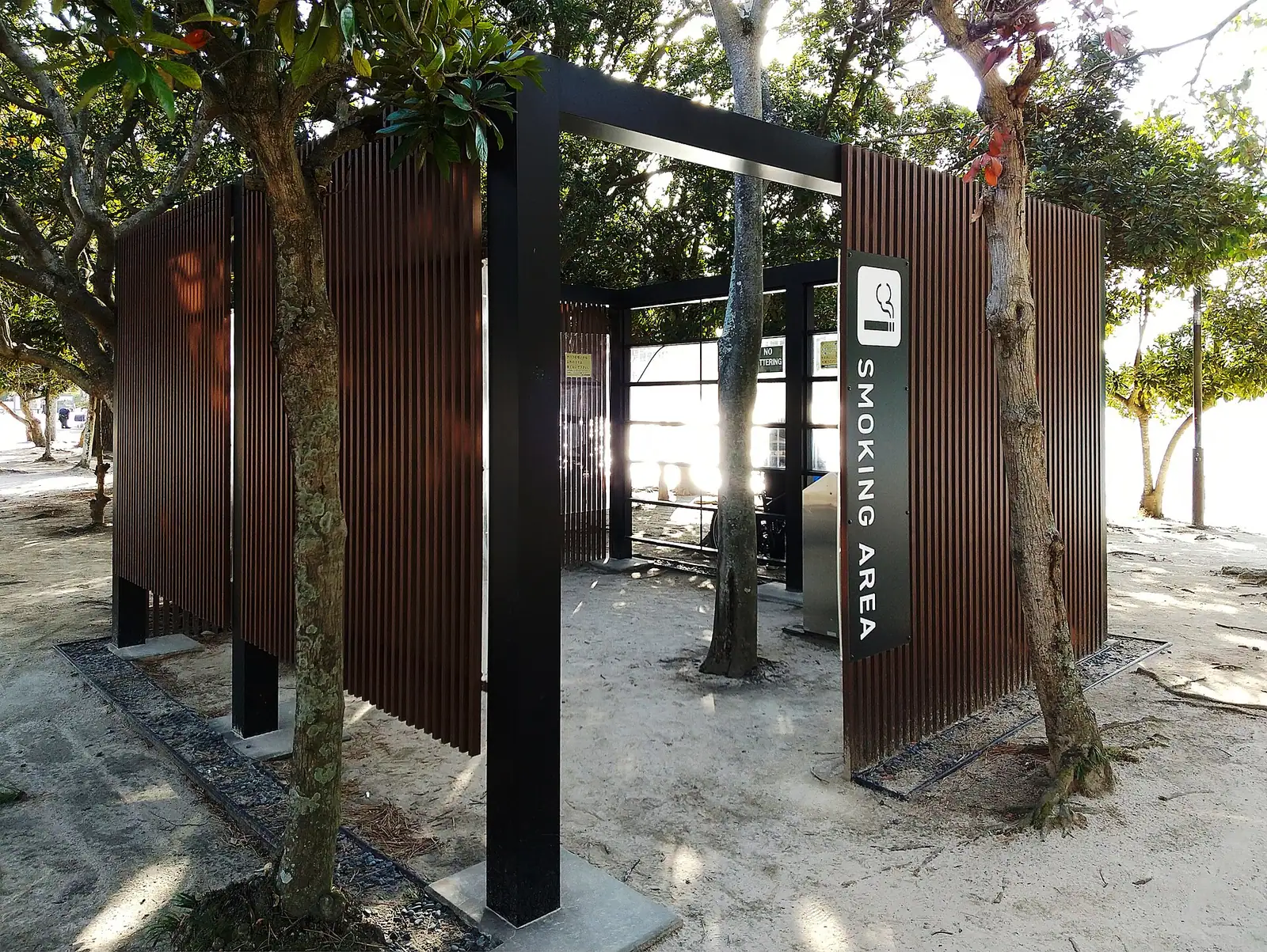 Outdoor designated smoking area in Ohori Park, Fukuoka, semi‑open wooden‑slatted wooden‑frame design with a SMOKING AREA sign