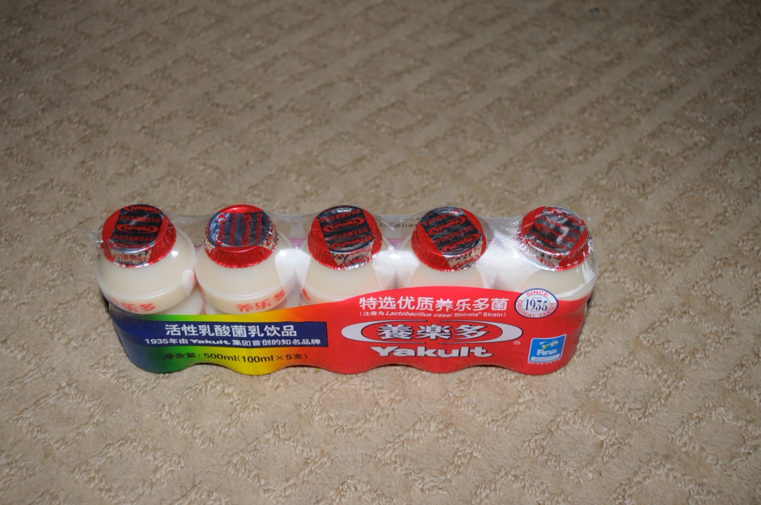 五瓶塑膠小瓶裝養樂多並排,紅白包裝的養樂多是台灣家庭冰箱常見的乳酸菌飲料