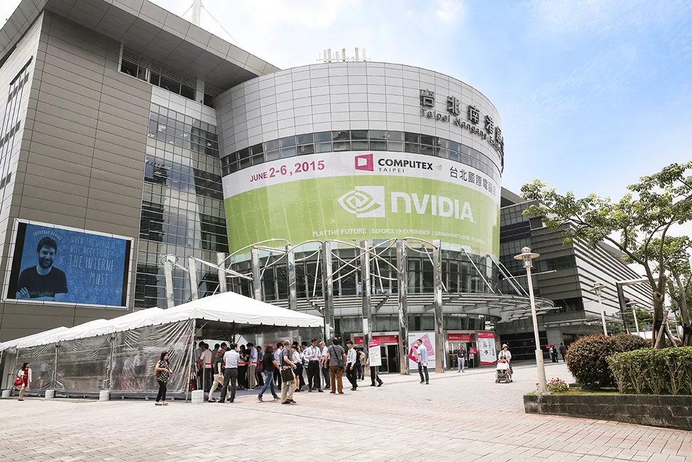 台北南港展覽館 Computex 展場，寬闊走道兩側排滿資訊廠商攤位、人潮聚集