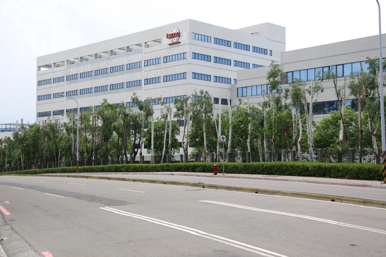 Exterior de una planta de TSMC en el Hsinchu Science Park; grandes edificios beige de salas limpias que constituyen una de las principales bases de producción de chips avanzados del mundo